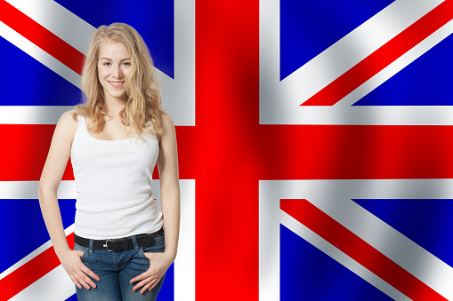 Portrait of happy pretty girl with the UK flag background. Young woman learning english language and traveling in United Kingdom