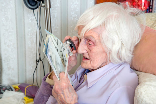istock Visually impaired elderly woman reading with magnifying loupe. 1189335847