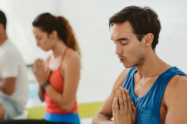 istock Young man sitting in a yoga class and meditating 1189338238