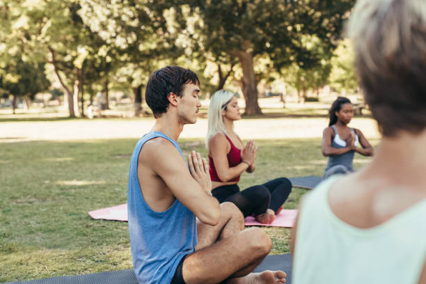 istock Young man meditating with others while doing yoga together outdoors 1189338332