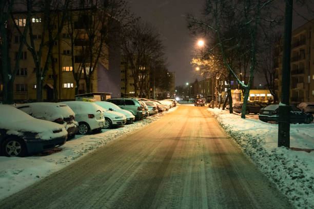 traffic in the city at snowy winter night. snow-covered cars standing in the parking lot. - street light parking lot night lot imagens e fotografias de stock