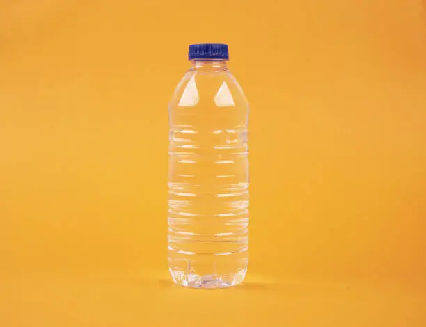 Photo of Water in plastic bottle on isolated yellow background
