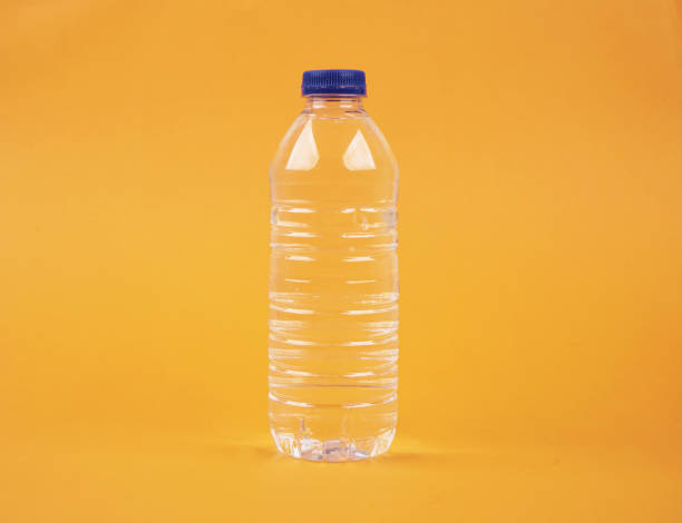 água no frasco plástico no fundo amarelo isolado - distilled water - fotografias e filmes do acervo