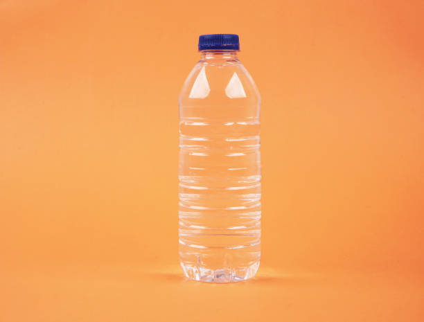 istock Water in plastic bottle on isolated orange background 1189338628