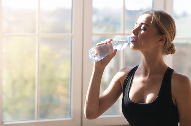 istock Sporty girl drinking water while exercising at yoga studio 1189339548