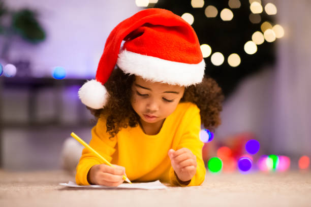 istock African kid writing wishlist, lying on floor near Christmas tree 1189339757