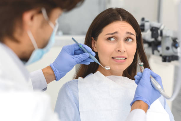 Scared woman at dental office, looking panickly at dentist Dentophobia concept. Scared young woman looking at dentist phobia stock pictures, royalty-free photos & images