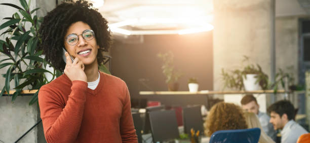 istock Positive black guy talking on cellphone at office 1189339910