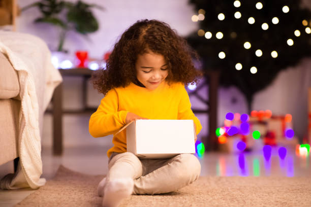 istock Stunned little african kid looking into Christmas gift box 1189340055