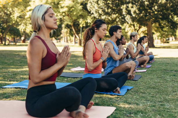 istock Yoga students sitting outside in a park and meditating 1189341391