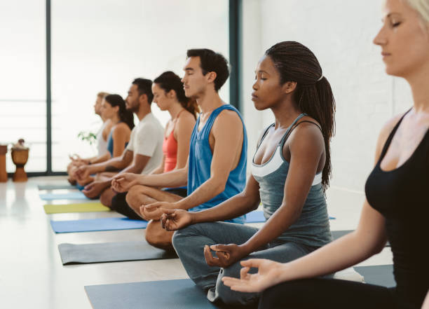istock Yoga students sitting in the lotus pose during yoga class 1189342194