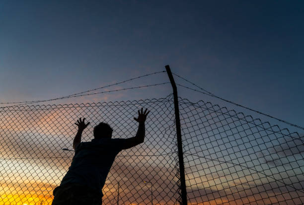 istock Refugee man running behind fence, 1189344474