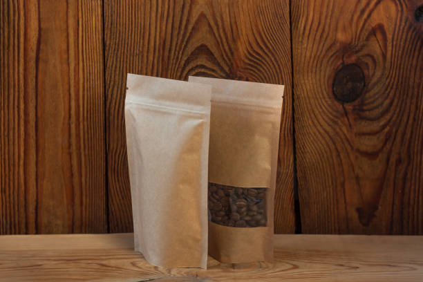 木製の背景にコーヒー豆の正面図を持つ茶色のクラフト紙ポーチバッグ。食品や商品の包装。 - paper rough kraft foods brown ストックフォトと画像