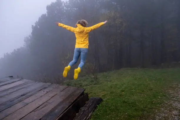 Photo of Playful Young Adult Woman jumping in the air in the Misty Mountains