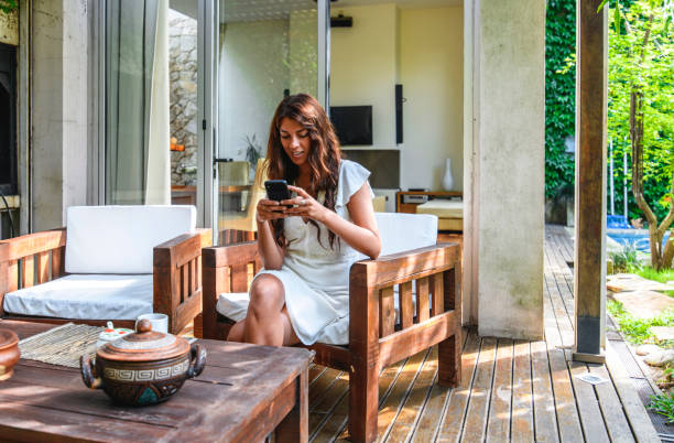 istock Young Hispanic Woman Sitting on Outdoor Deck and Texting 1189350198
