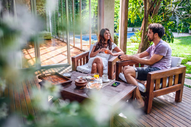 Breakfast and Relaxing Conversation on Home Deck Personal perspective of young couple sitting outside on home deck and enjoying leisurely breakfast and conversation with backyard in background. drinks on the deck stock pictures, royalty-free photos & images
