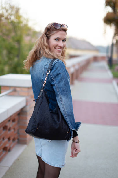 istock Young cheerful woman looking back during walk in park 1189353566