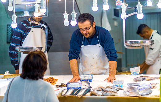 Employee attending a customer at the La Herradura fish market in Andalusia, Southern Spain