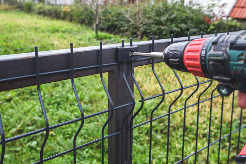 Man hand Screwing grating wire industrial fence panels