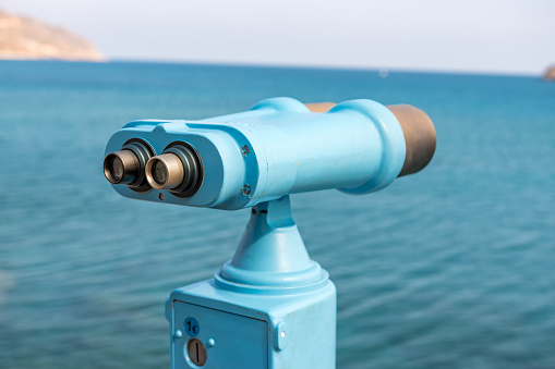 Telescope looking out over water and coastline on sunny day, focus on eye piece. Shot at Loch Ness, Scotland. Need clarity or to better see the future?