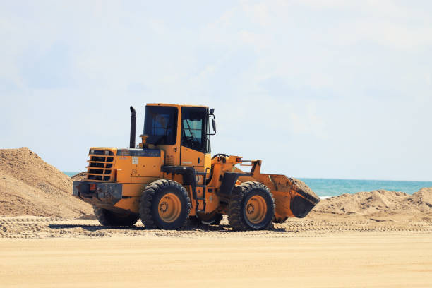 A tractor shoveling sand on the beach A tractor shoveling sand on the beach sand mine stock pictures, royalty-free photos & images