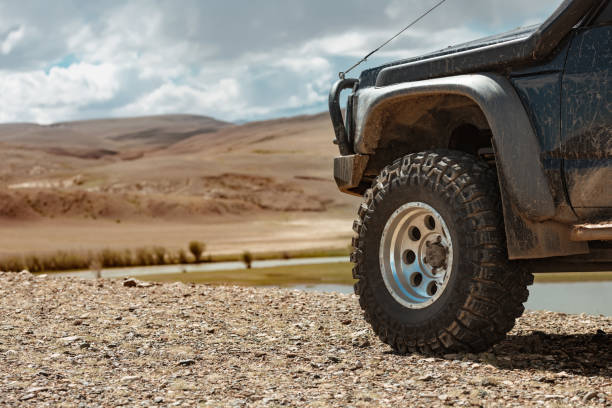 Aggressive off road ready car in mountains Aggressive off road ready car in mountains. Closeup photo of mud terrain wheel 4x4 stock pictures, royalty-free photos & images