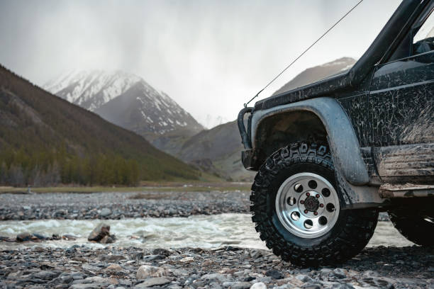 Big extreme offroad ready car Big extreme offroad ready car wheel against mountains and river altai nature reserve photos stock pictures, royalty-free photos & images
