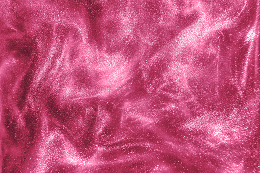 Abstract elegant, detailed pink glitter particles flow with shallow depth of field underwater. Holiday magic shimmering luxury background. Festive sparkles and lights. de-focused.