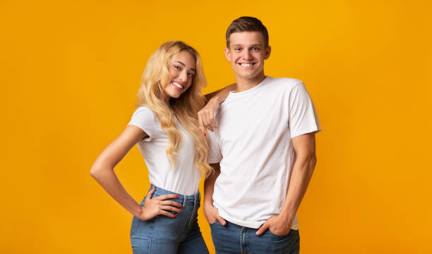 istock Smiling young couple posing in studio over yellow background 1189361660