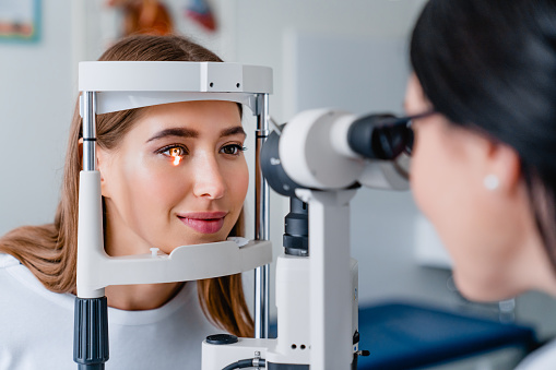 Médico oftalmológico con paciente femenino durante un examen en la clínica moderna photo