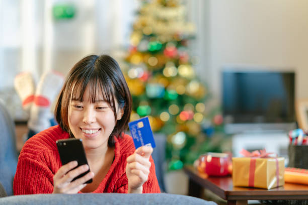 giovane donna che fa shopping natalizio online con carta di credito - smart phone china mobile phone asia foto e immagini stock