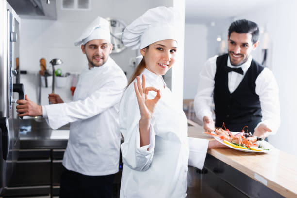 istock Smiling woman chef approving dish in kitchen of fish restaurant before serving guests 1189363803