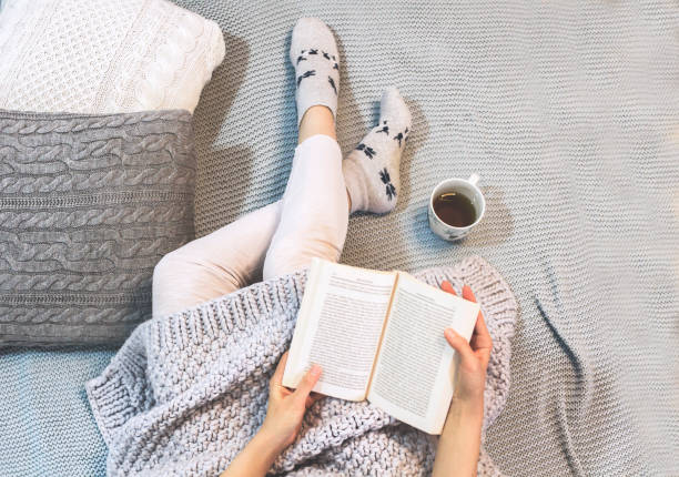 istock Young woman on a bed holding a book 1189366444