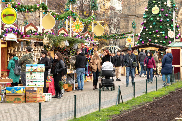 People looking at Christmas Stall at outdoor market in Prague Europe Prague Europe The Czech Republic 11-22-2019. People by the outdoor Christmas stalls at the Square Namesti Miru in Prague. Background Christmas Tree and Christmas decoration of the area. prague christmas market stock pictures, royalty-free photos & images
