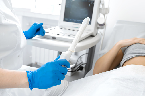 Un ginecólogo instala una máquina de ultrasonido para diagnosticar a un paciente que está acostado en un sofá. Un ecografía transvaginal de los órganos internos de la pelvis. Concepto de salud femenina photo