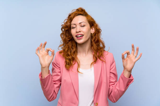 istock Redhead woman in suit over isolated blue wall in zen pose 1189368029
