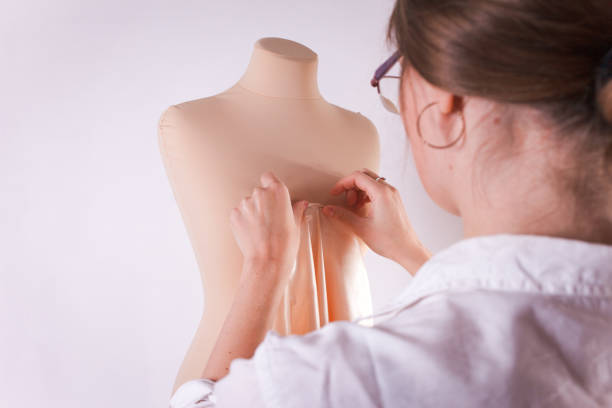 istock Seamstress cuts fabric with big scissors on a mannequin. 1189368482