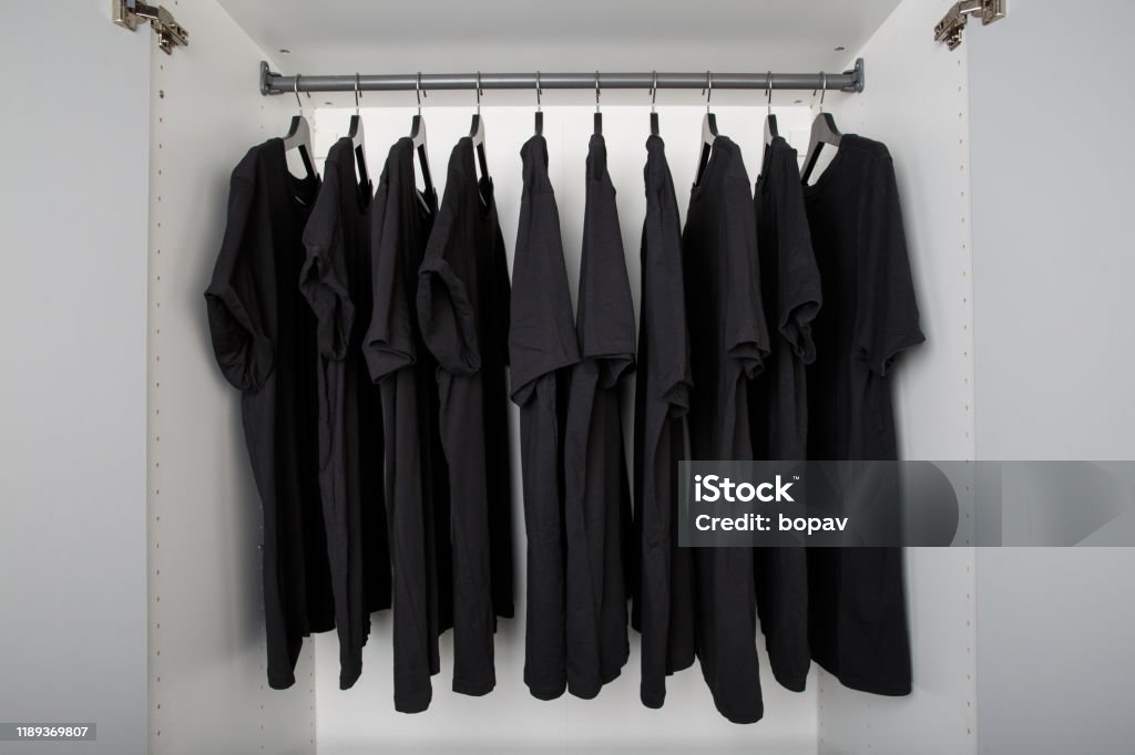black shirts on hangers in a row boring wardrobe with same black color shirts on hangers Black Color Stock Photo