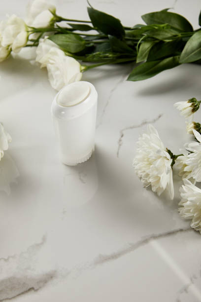 istock selective focus of roll on bottle of deodorant with flowers on white marble surface 1189373076