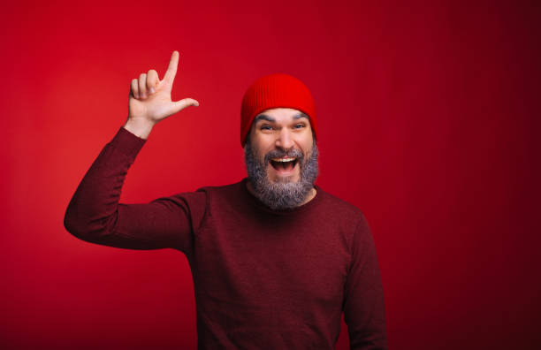istock Cheerful handsome bearded hispter man pointing at copyspace over red background 1189376740