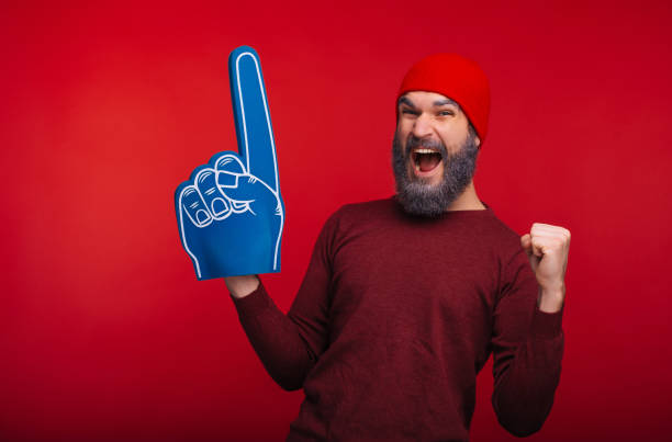 istock Amazed bearded hipster man standing over red background and celebrating success with fan finger glove 1189376849