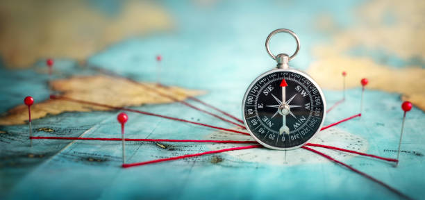 istock Magnetic compass  and location marking with a pin on routes on world map. 1189377155
