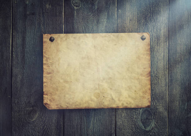 istock Old blank parchment on aged wood background and light rays. 1189377542