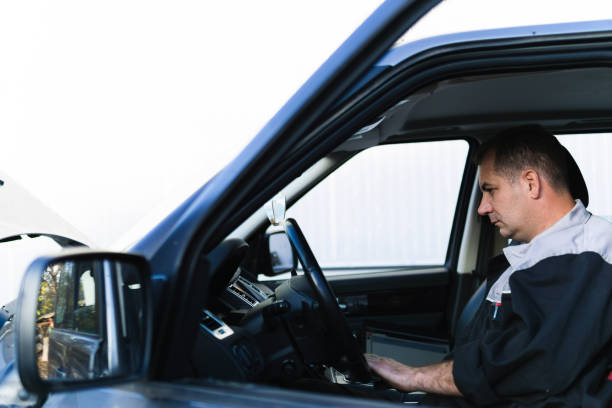 istock Professional auto mechanic sitting in a car and using laptop to check car diagnostics. 1189384854