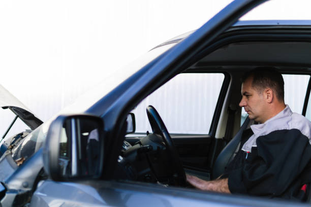 istock Professional auto mechanic sitting in a car and using laptop to check car diagnostics. 1189384947