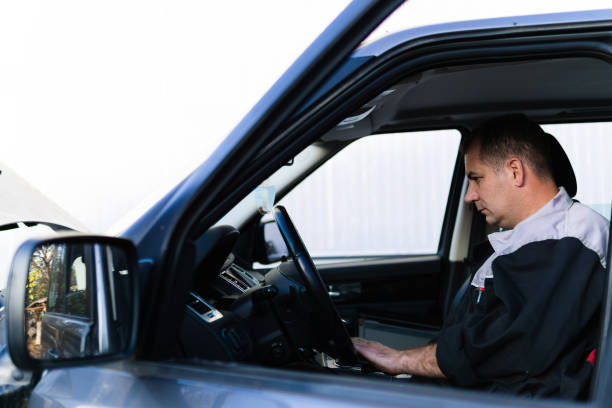 istock Professional auto mechanic sitting in a car and using laptop to check car diagnostics. 1189385520