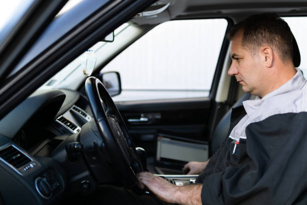 istock Professional auto mechanic sitting in a car and using laptop to check car diagnostics. 1189387398