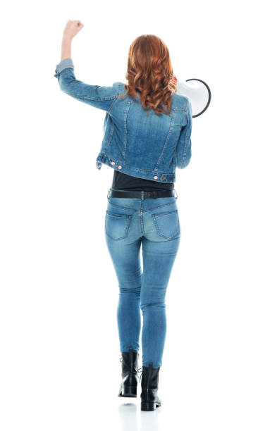 full length / rear view / back / one person of 20-29 years old adult beautiful redhead caucasian female / young women walking wearing double denim / jeans / pants / denim jacket / boot / rolled-up sleeves / jacket / warm clothing - one young woman only only young women one woman only 20 25 years imagens e fotografias de stock