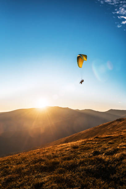 istock yellow paraglider flying in the sky on sunset 1189390681