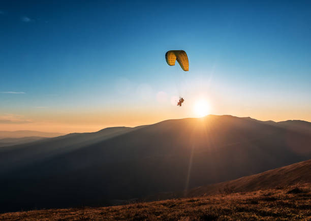 paragliders flying in the sky above the mountains - airplane sky extreme sports men imagens e fotografias de stock